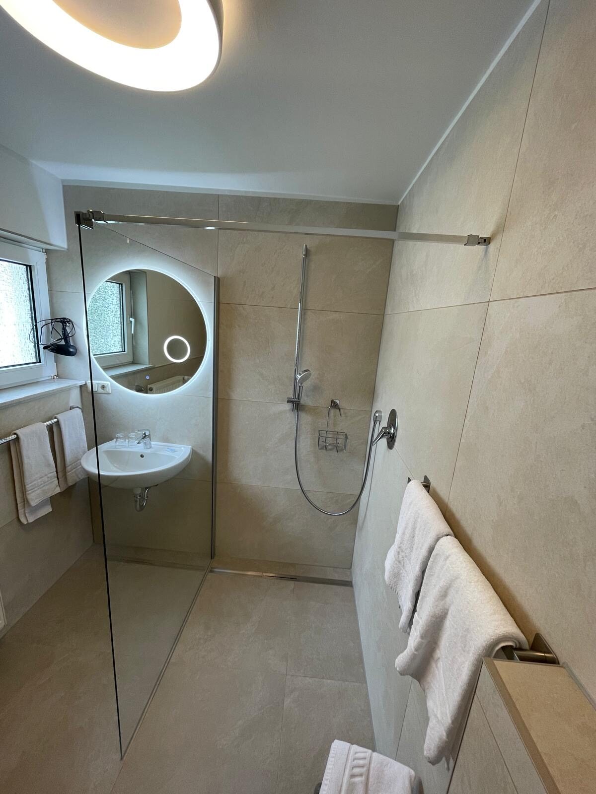 Modernes Bad mit Walk-in-Dusche und Rundspiegel im Landhaus Schend