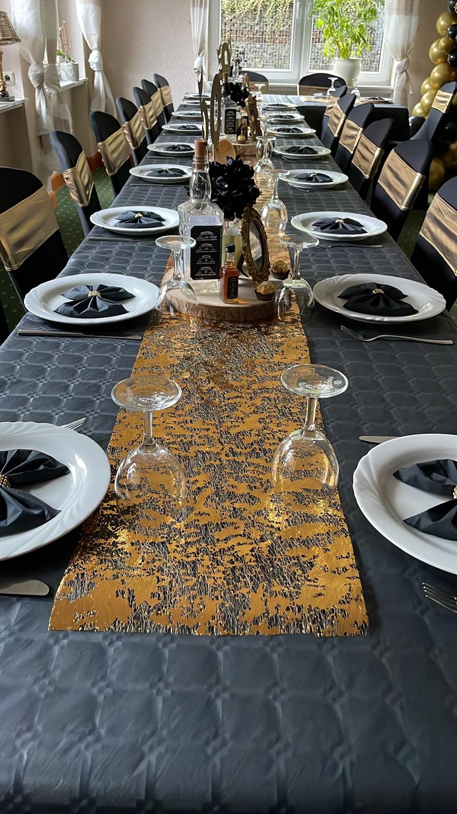 Table de fête dressée au Landhaus Schend avec chemin de table doré, serviettes noires et flûtes à champagne