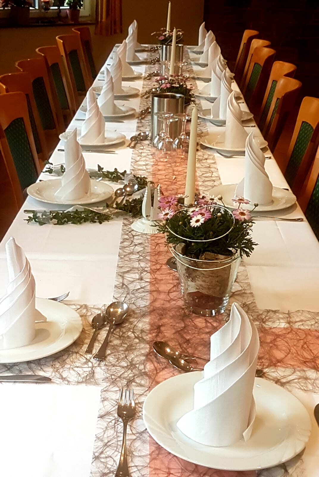 Lange Festtafel im Saal des Landhauses Schend, weiß eingedeckt mit Kerzen, Blumen und gefalteten Servietten