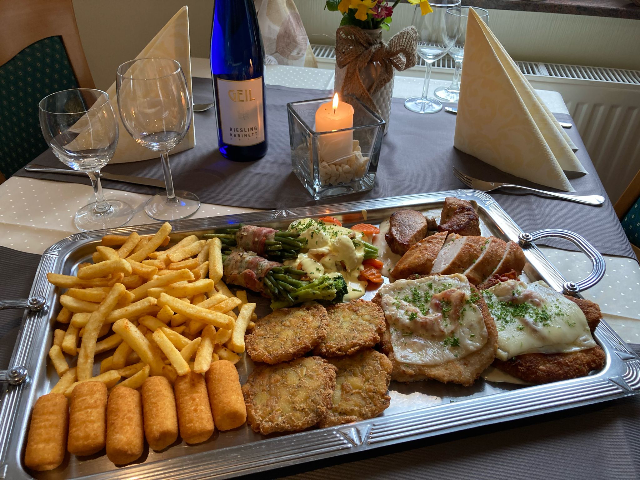 Gedeckter Tisch im Landhaus Restaurant Schend mit Schnitzelteller, Beilagen und einem Glas Wein