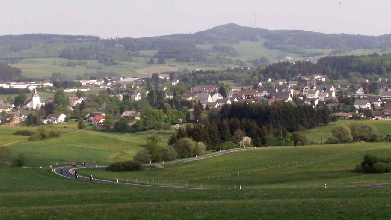 Geschwungene Landstraße durch die Wiesen bei Kelberg in der Eifel